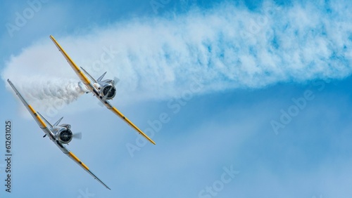 Two airplanes flying in the blue skies during an air show in bright sunlight with a copy space