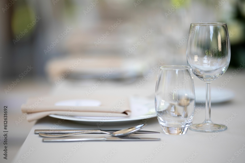 Closeup of a festive table with white dishes and glasses, blurred background, just married