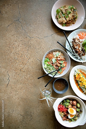 Vertical top view of bowls of gourmet Asian dishes on a brown table with copy space