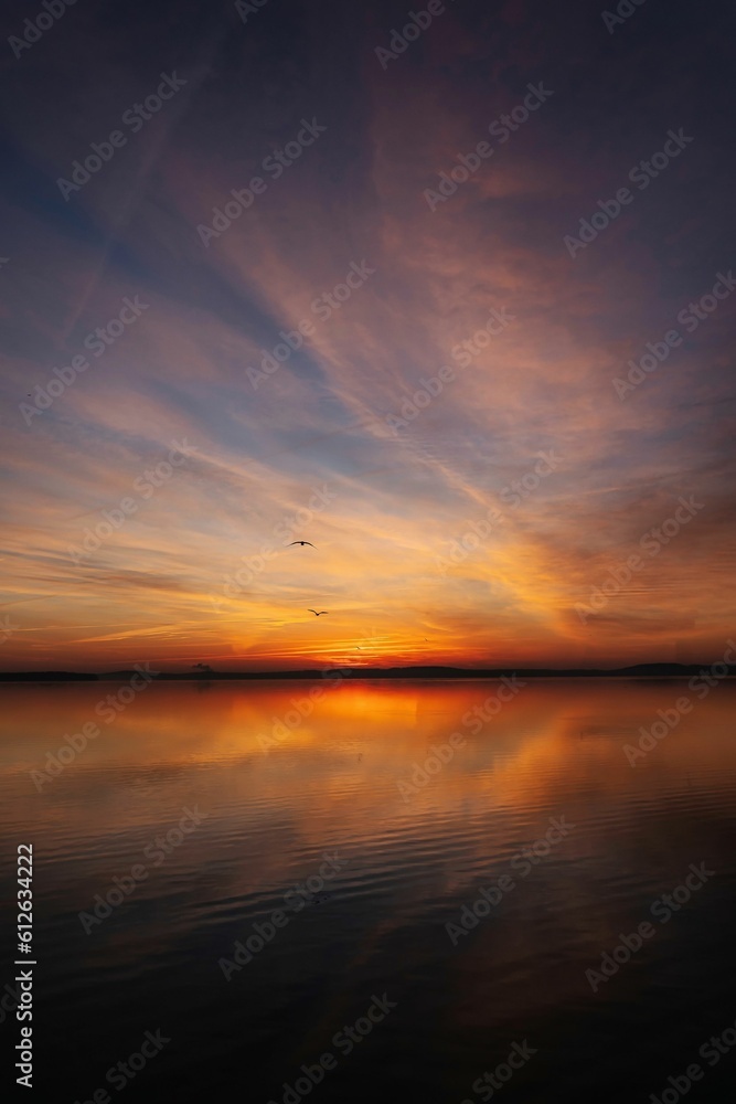 a sunset in the middle of a lake with an orange sky