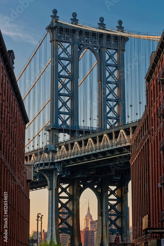 Vertical shot of the Brooklyn bridge seen through buildings in New York, U.S. © Almasig/Wirestock Creators