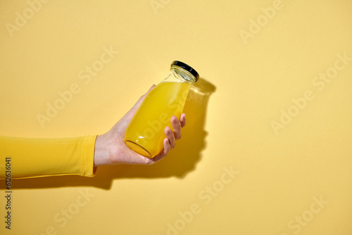 Female hand with a bottle of juice on color background photo