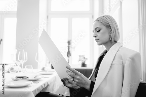 Blond woman reading menu in restaurant
 photo