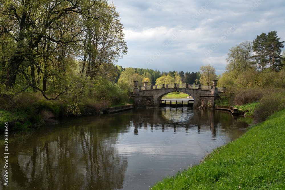 View of the Slavyanka River and the Viscontiev Bridge in the Pavlovsk Palace and Park Complex on a sunny spring day, Pavlovsk, Saint Petersburg, Russia