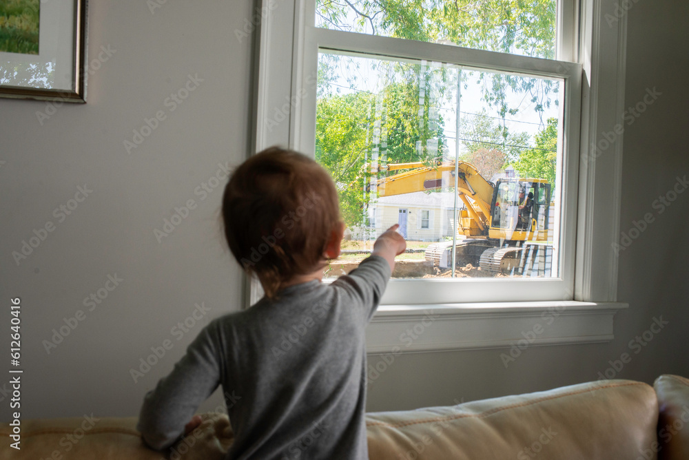 Child Pointing out the Window at an Excavator Outside his House Child Pointing out the Window at an Excavator Outside his House