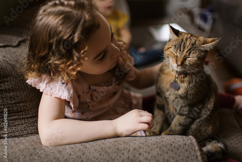 Girl petting her cat while sitting on couch 
