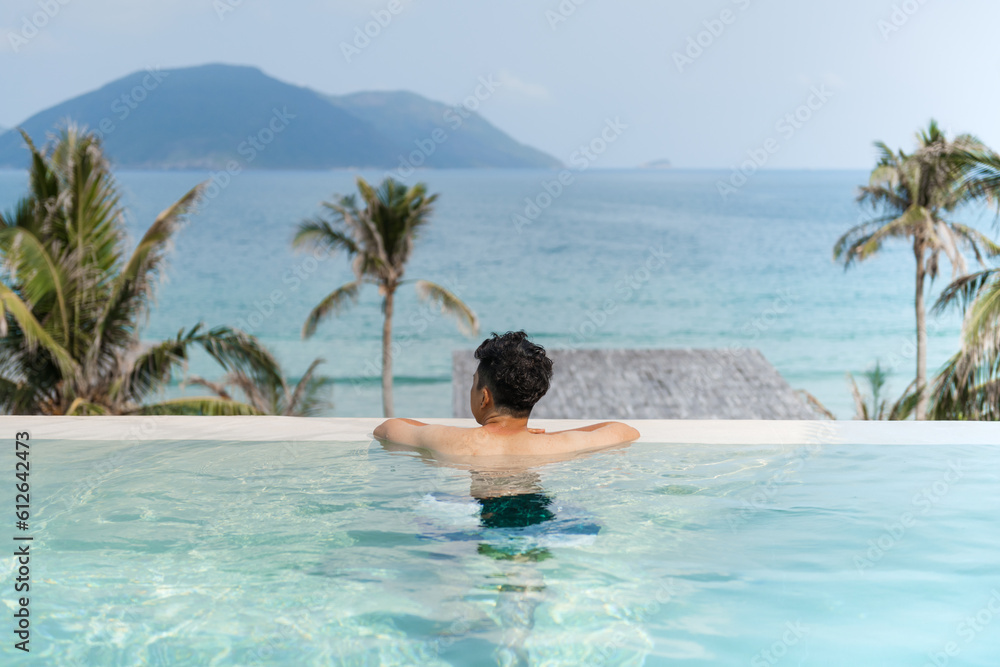 man relaxing in luxury pool on hill top near sea beach man relaxing in luxury pool on hill top near sea beach