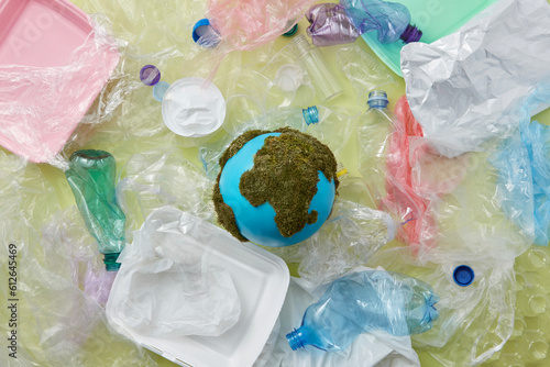Earth globe laid amidst various waste. photo