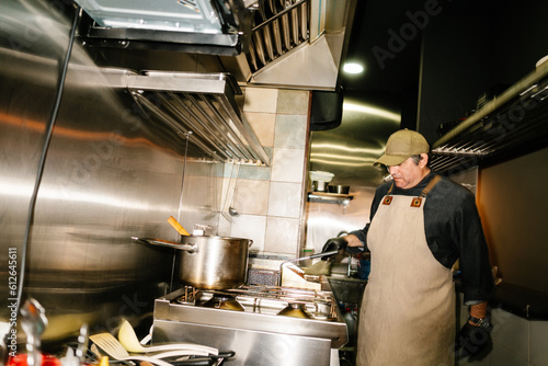 Male cooking in stainless steel kitchen of restaurant photo