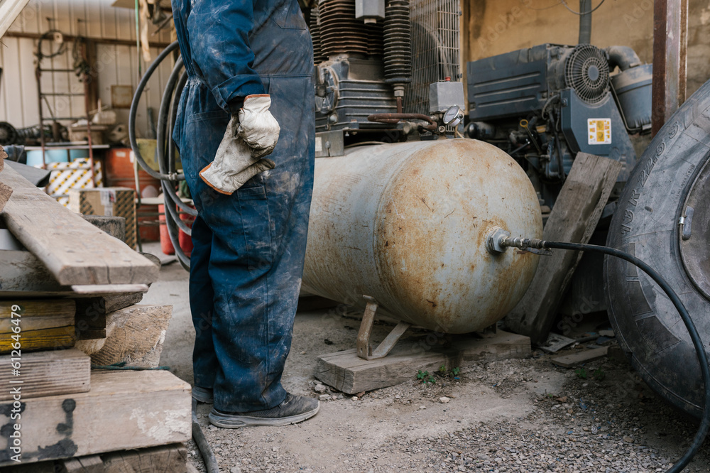 Crop worker standing near compressor in garage Crop worker standing near compressor in garage