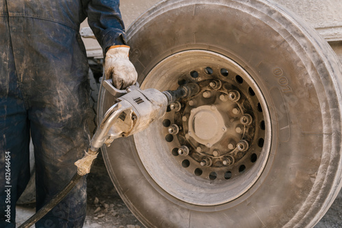Mechanic tightening bolts on wheel with impactor