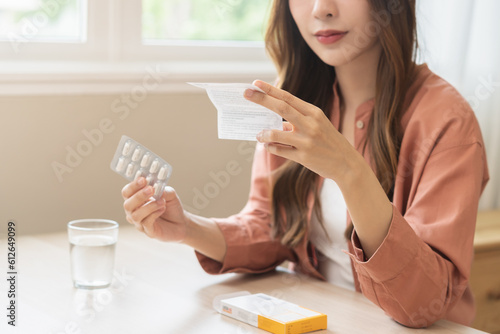 Health care treatment asian young woman holding prescription of capsule medicine, reading label text about medical information, looking medicine instruction side effects, pharmacy medicament concept. photo