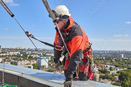 A specialist repairs an antenna on the roof. Rope access