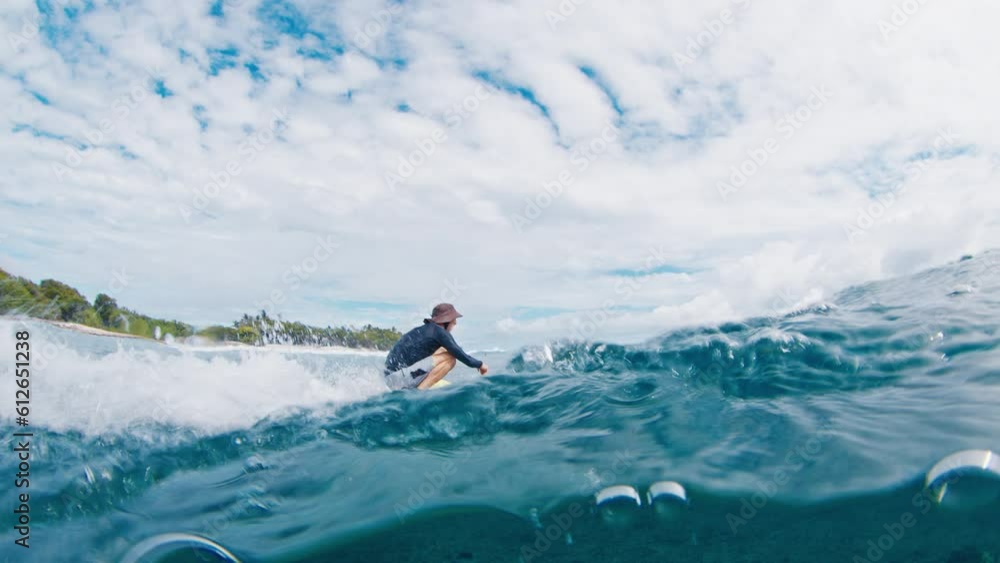 Adult male surfer rides the wave, looks into the camera and touches it while passing by Adult male surfer rides the wave, looks into the camera and touches it while passing by