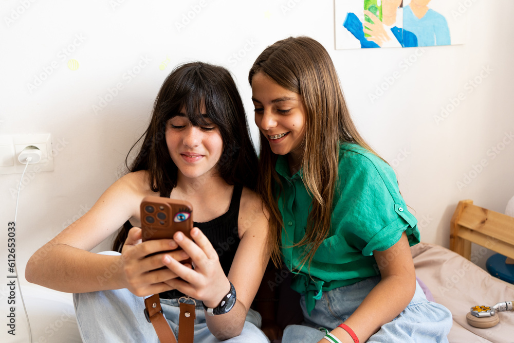 Young girl friends smiling watching mobile phone Young girl friends smiling watching mobile phone