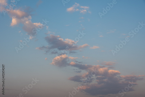 sunset sky with pink clouds, diagonally stripe, grey above. Whispy pink clouds and blue sky diving frame diagonally. Cirrus and cirrocumulus clouds form a colored triangle.