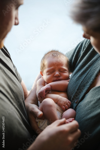 Sleeping newborn with both parents holding it. photo