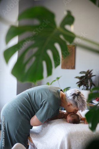 Mother cuddling and kissing newborn baby at home. photo