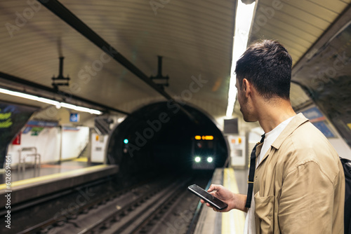 Young man waiting for the train standing on the subway platform