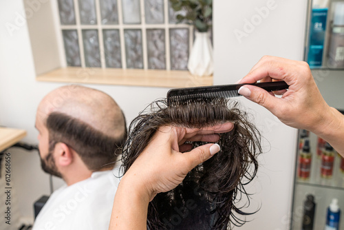 woman hairdresser combing hair prosthesis before fitting it to the cus photo