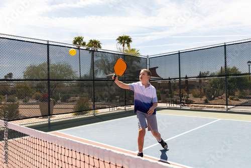 Young boy Pickleball player looks to hit swing at ball  photo