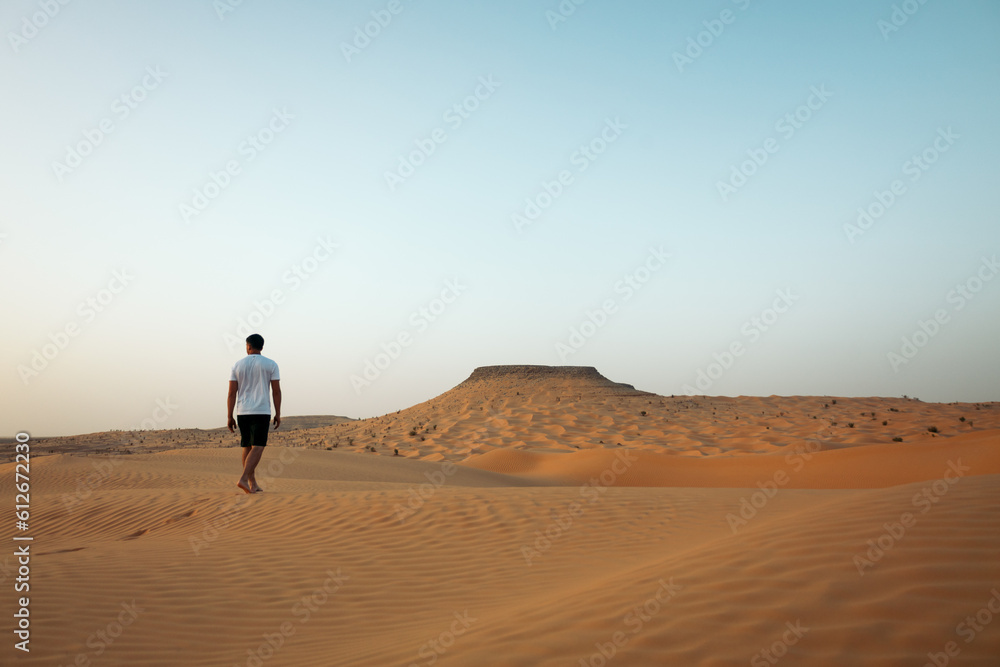 Man walking through the dunes of the Sahara desert Man walking through the dunes of the Sahara desert