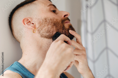 Man at home trimming his beard