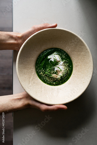 Hands holding freshly cooked organic nettle tops cream soup photo