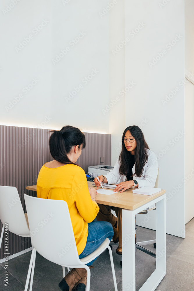 Diverse women focused on consultation in IVF lab. Diverse women focused on consultation in IVF lab.