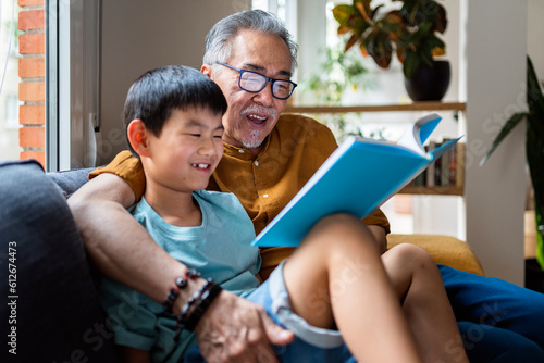 Grandpa reading book to smiling grandson. photo