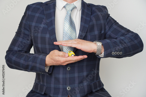 Businessman's Hand Protecting Small Yellow Toy Car On The. Car insurance concept