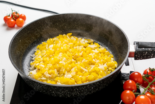 A frying pan with Chopped Bell Peppers and Onions is fried on the Stove. Recipe and cooking process for Shakshuka and Menemen. Step by step. Fifth photo.