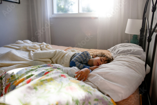 Boy sleeps in sun filled room photo