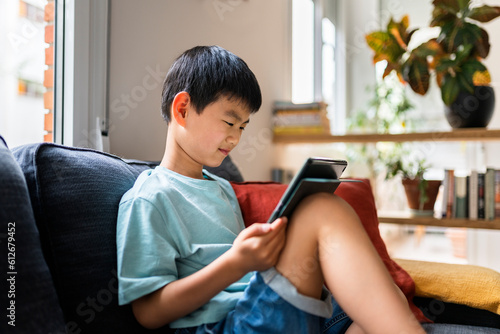 Serious Chinese boy playing tablet game. photo