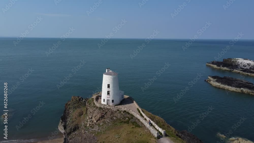 Establishing aerial view Ynys Llanddwyn coastal walking trail towards Goleudy Tŵr Mawr stone lighthouse and Snowdonia mountains, Anglesey Establishing aerial view Ynys Llanddwyn coastal walking trail towards Goleudy Tŵr Mawr stone lighthouse and Snowdonia mountains, Anglesey