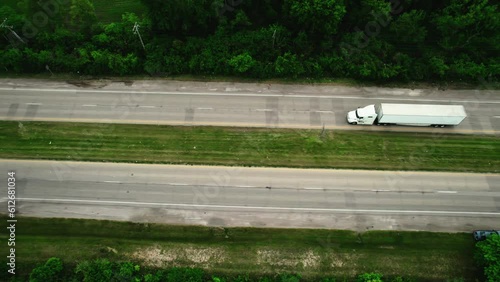 unique aerial of a semi truck and trailer turning left sorounded by green foliage.  Cinematic aerial, Wisconsin USA 4k photo