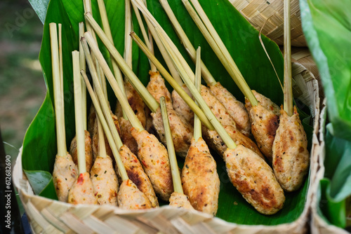 Balinese fish satay plated in a bamboo basket lined with banana leaf photo