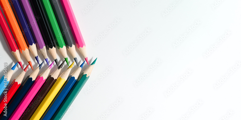 Colored pencils lying over paper, flat lay. Colored pencils lying over paper, flat lay.