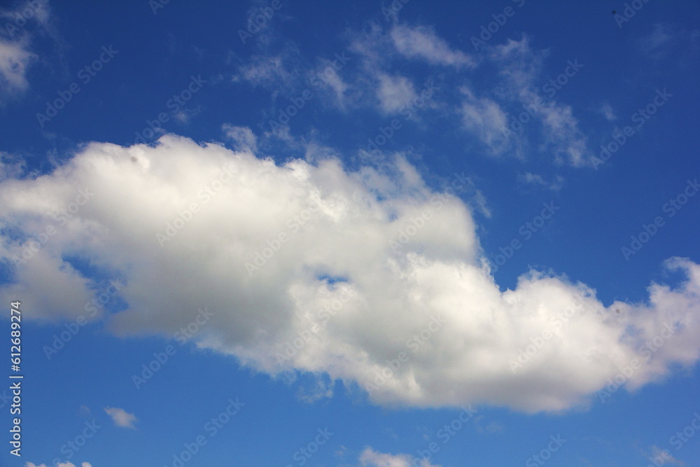 Big white cloud against the blue sky on a hot summer day. Illustration of the weather forecast.