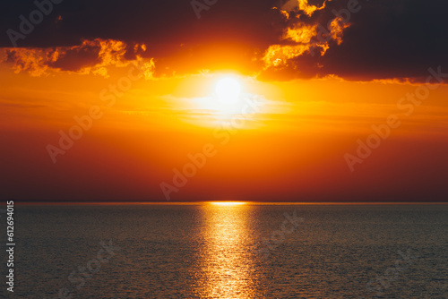 majestic clouds and orange sun over the ocean