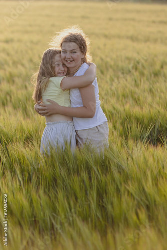 two pre-teen girls happy hugging in a field of rye in nature