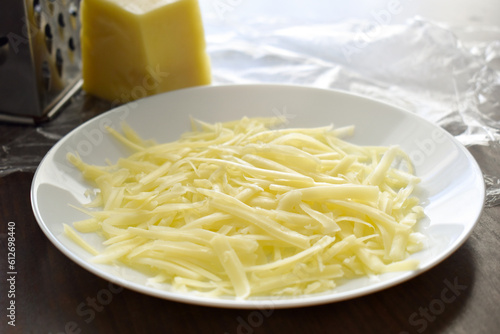 Grated cheese on a white plate.  Cooking food preparation concept. 