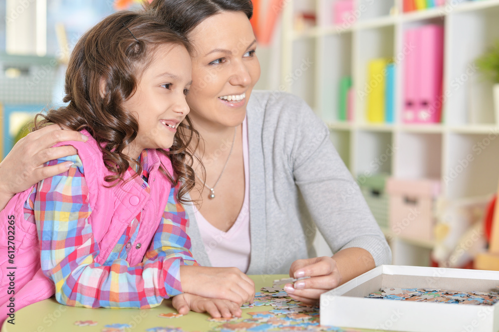 Fototapeta premium Mother with little daughter collecting puzzle