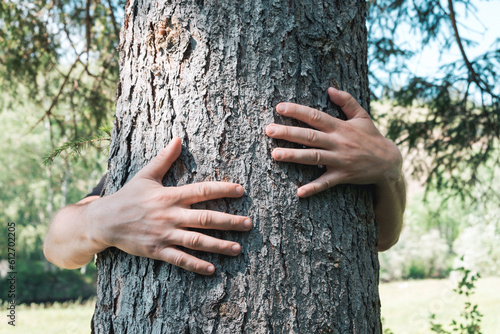 Man hugging tree bark on the summer forest. Ecology concept, love and care nature, climate change. Earth Day. Closeup