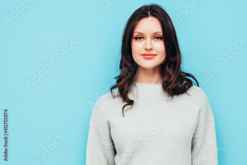 Young beautiful smiling female in trendy summer jeans and sweater clothes. Sexy carefree woman posing near blue wall in studio. Positive model isolated. Cheerful and happy