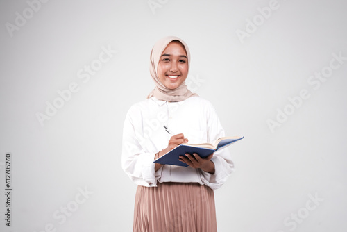 Muslimah college carrying book and pen for studying isolated white background