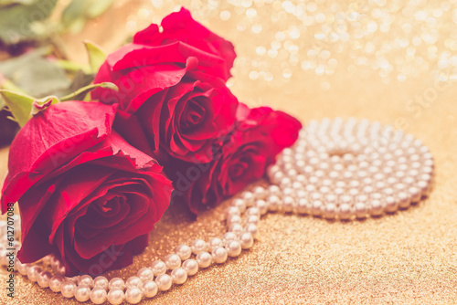 Red rose and pearl necklace on a shiny gold background
 photo