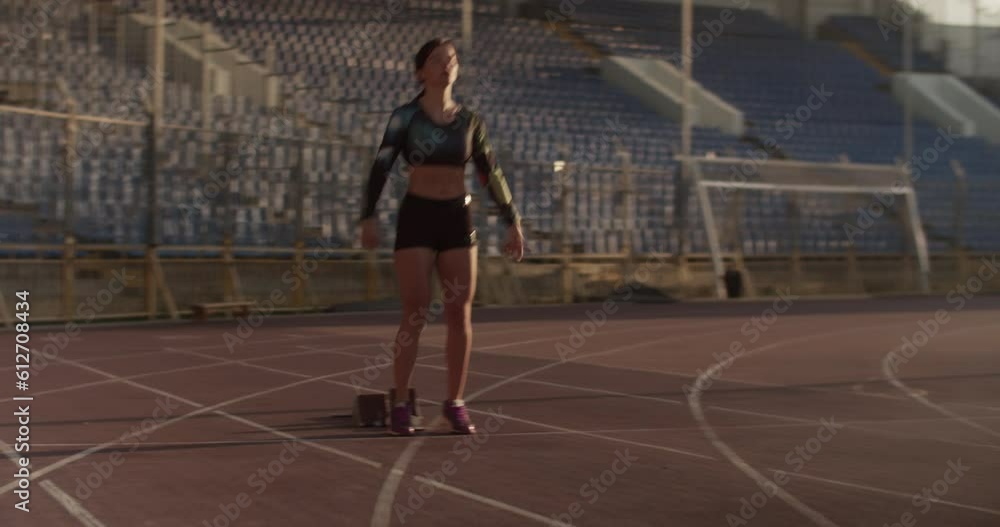 Young female sprinter preparing for run in stadium Young female sprinter preparing for run in stadium