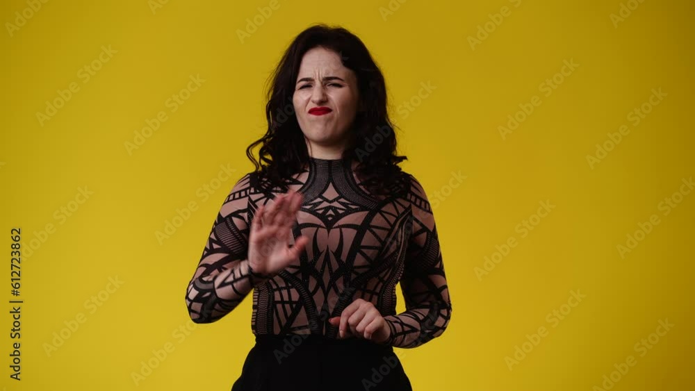 4k video of one girl showing stop sign over yellow background. 4k video of one girl showing stop sign over yellow background.