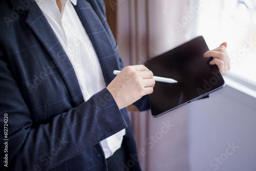close-up women holding digital tablet black screen and stylus pen on light windows